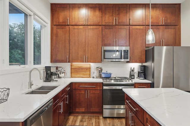 461 Rayner Ave, Fort Worth, TX 76111 - kitchen featuring stainless steel appliances, a sink, decorative backsplash, light stone counters, and hanging light fixtures