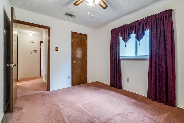 unfurnished bedroom with carpet, a textured ceiling, and a ceiling fan