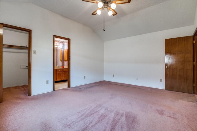 unfurnished bedroom with lofted ceiling, a walk in closet, carpet floors, ensuite bath, and a closet