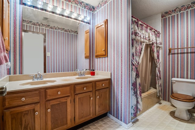 bathroom featuring wallpapered walls, toilet, tile patterned floors, a textured ceiling, and double vanity