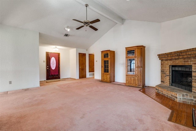 unfurnished living room featuring beam ceiling, a brick fireplace, ceiling fan, light carpet, and high vaulted ceiling