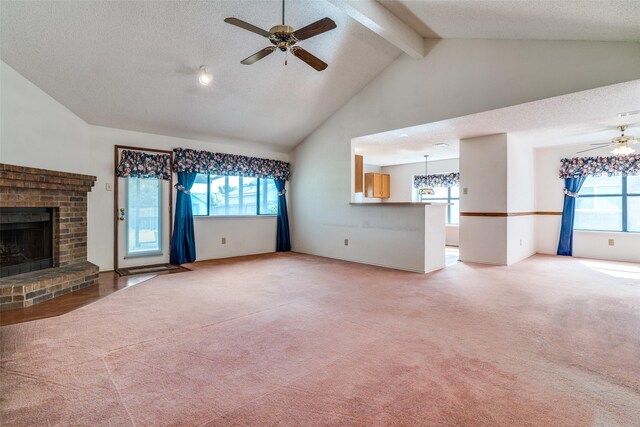 unfurnished living room featuring ceiling fan, a fireplace, light colored carpet, healthy amount of natural light, and beamed ceiling