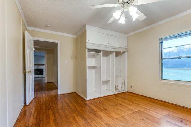 1455 N Joe Wilson Rd, Cedar Hill, TX 75104 - unfurnished bedroom featuring light wood-style flooring, a fireplace, a closet, a textured ceiling, and a ceiling fan
