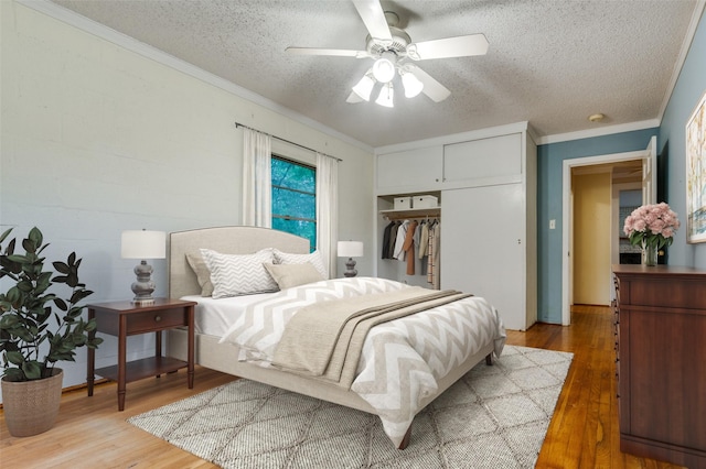 1455 N Joe Wilson Rd, Cedar Hill, TX 75104 - bedroom with light wood-style flooring, a closet, a textured ceiling, crown molding, and a ceiling fan