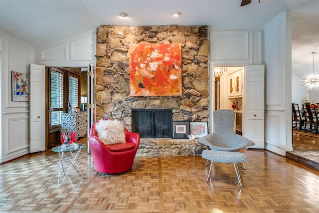 sitting room with a decorative wall, a stone fireplace, a chandelier, and lofted ceiling
