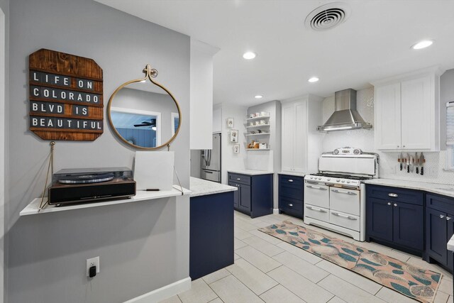 kitchen featuring wall chimney range hood, double oven range, blue cabinets, washer / dryer, and white cabinets