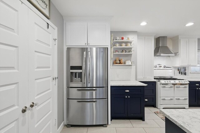 kitchen with stainless steel fridge with ice dispenser, wall chimney exhaust hood, double oven range, white cabinets, and backsplash