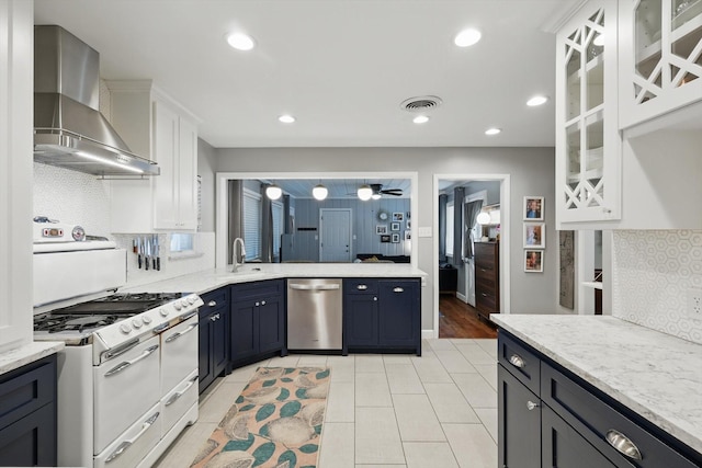 kitchen featuring stainless steel dishwasher, wall chimney exhaust hood, range with two ovens, white cabinets, and backsplash