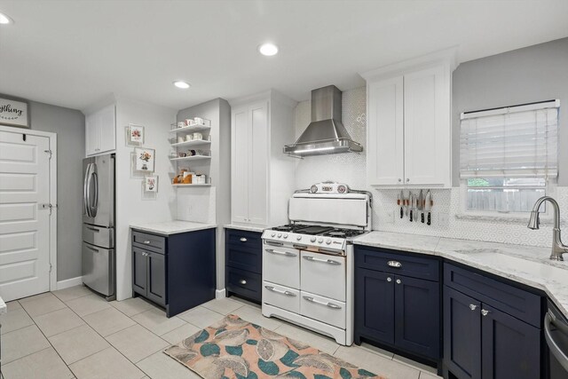 kitchen featuring double oven range, wall chimney exhaust hood, freestanding refrigerator, white cabinetry, and backsplash