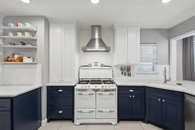 kitchen with double oven range, wall chimney range hood, a sink, stainless steel dishwasher, and blue cabinetry