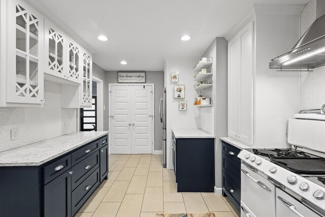 kitchen with wall chimney range hood, double oven range, white cabinets, decorative backsplash, and glass insert cabinets