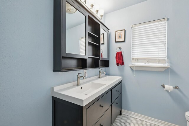 bathroom featuring double vanity, baseboards, and toilet
