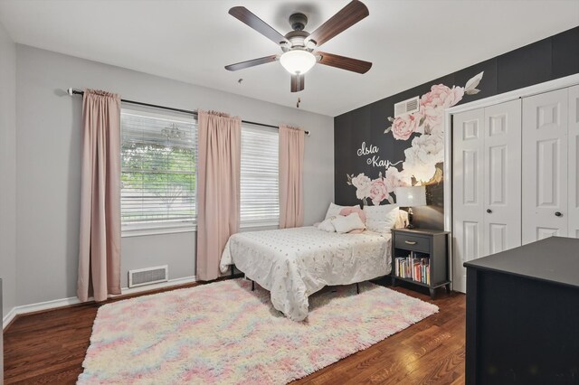 bedroom with a closet, dark wood-style flooring, a ceiling fan, and baseboards