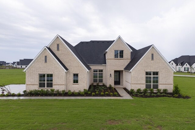 french country inspired facade featuring brick siding and a front lawn