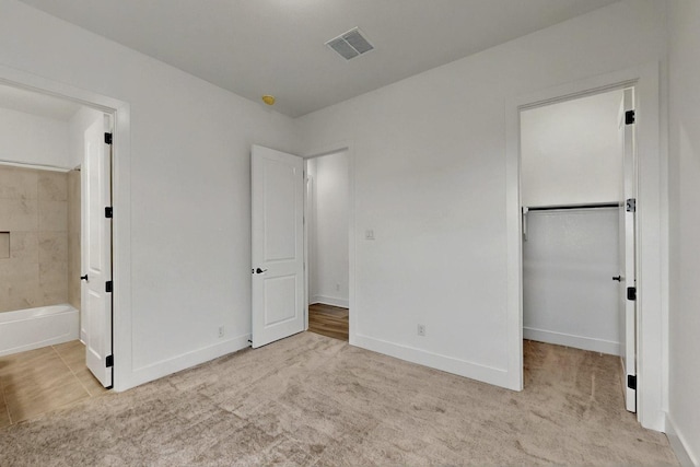 unfurnished bedroom with carpet floors, baseboards, and ensuite bathroom