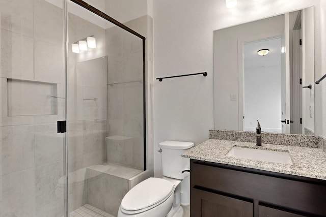 full bathroom featuring a shower stall, toilet, and vanity