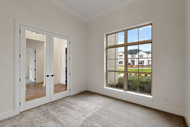 empty room with french doors, healthy amount of natural light, carpet, crown molding, and baseboards