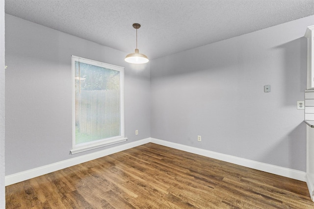 empty room with baseboards, dark wood finished floors, and a textured ceiling