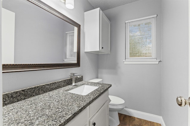 bathroom featuring wood finished floors, toilet, baseboards, and vanity