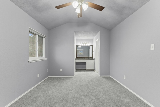 unfurnished bedroom with carpet floors, a textured ceiling, vaulted ceiling, baseboards, and ensuite bath