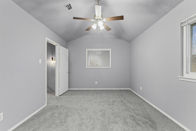unfurnished bedroom with carpet flooring, a textured ceiling, vaulted ceiling, baseboards, and a ceiling fan
