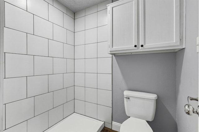 bathroom with toilet and tiled shower