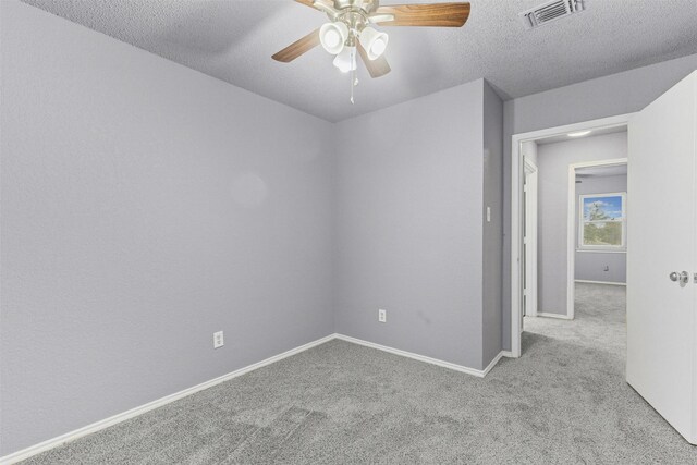 empty room featuring carpet flooring, a ceiling fan, baseboards, and a textured ceiling