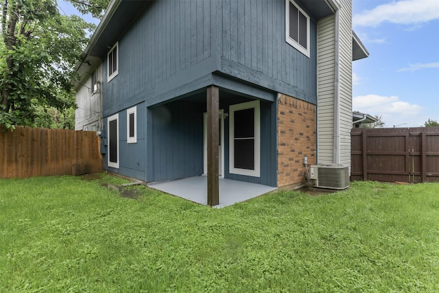 back of house with central AC unit, a patio, and brick siding