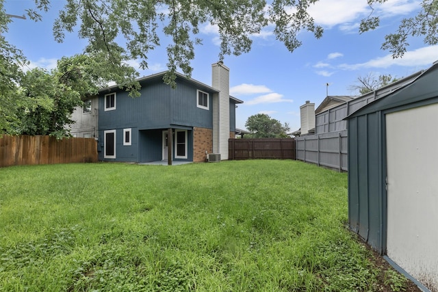 back of house featuring central AC unit, brick siding, and a chimney