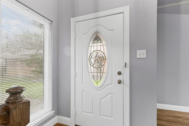 foyer entrance with baseboards, wood finished floors, and a textured wall