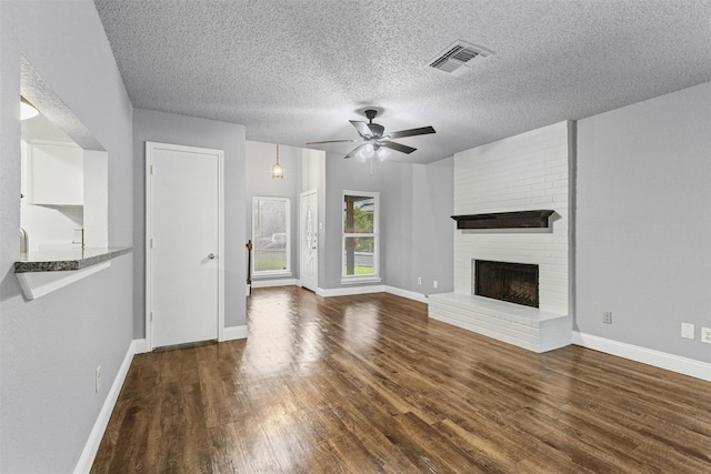 unfurnished living room featuring wood finished floors, ceiling fan, a textured ceiling, baseboards, and a fireplace
