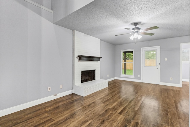 unfurnished living room with dark wood finished floors, ceiling fan, a textured ceiling, a fireplace, and baseboards