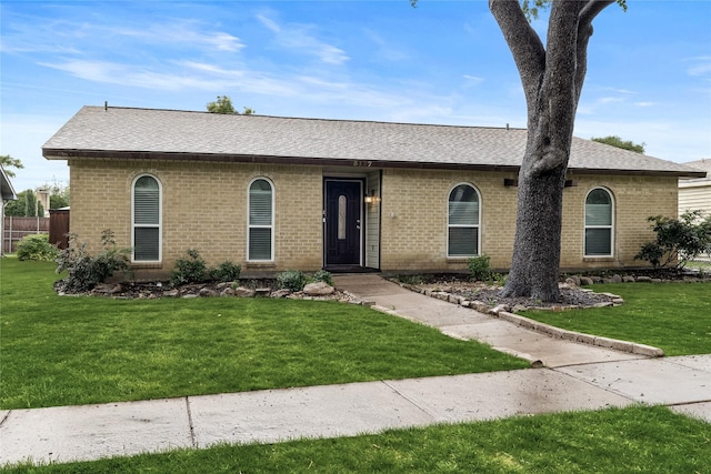 single story home with brick siding, a front yard, and a shingled roof
