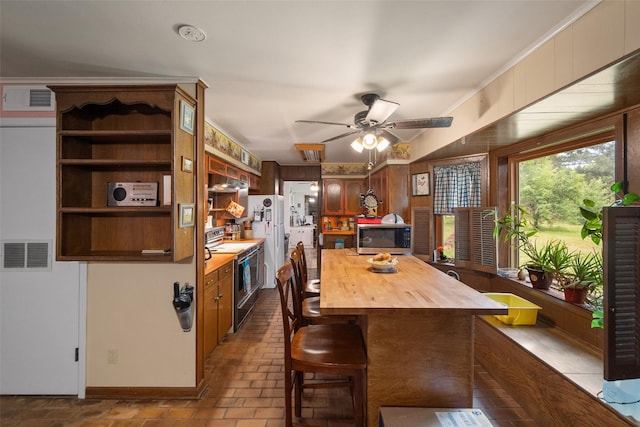 201 Sunset Dr, Fairfield, TX 75840 - kitchen featuring electric stove, stainless steel microwave, wood counters, ceiling fan, and a breakfast bar area