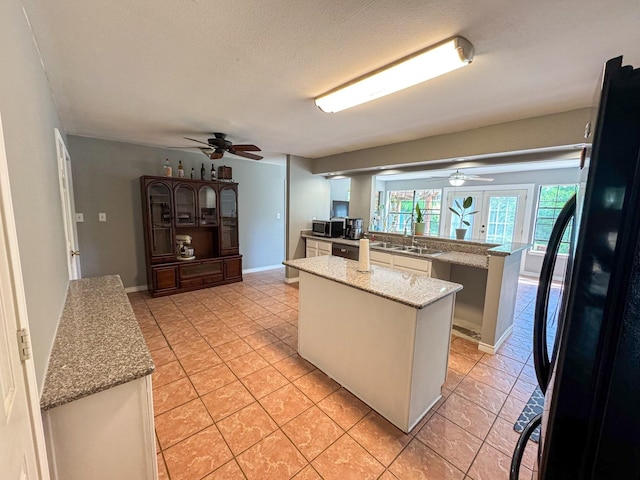 3836 Farm Road 196 N, Paris, TX 75462 - kitchen featuring freestanding refrigerator, ceiling fan, a sink, a center island, and stainless steel microwave