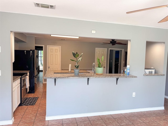 3836 Farm Road 196 N, Paris, TX 75462 - kitchen with a ceiling fan, a breakfast bar, a peninsula, range with two ovens, and light stone countertops