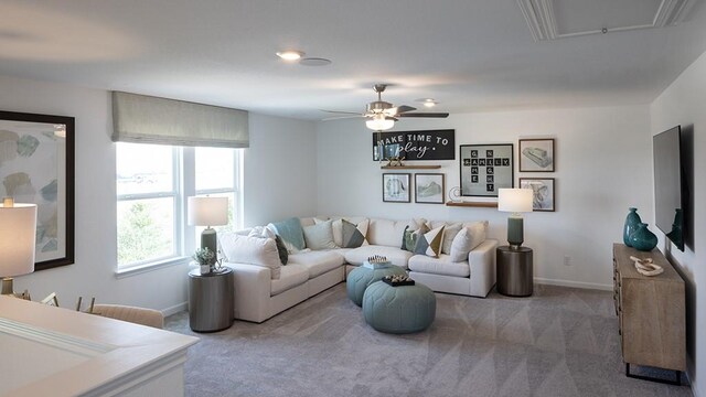 carpeted living area featuring baseboards, a ceiling fan, and attic access