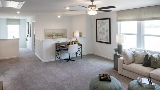 carpeted living area featuring attic access, ceiling fan, and baseboards