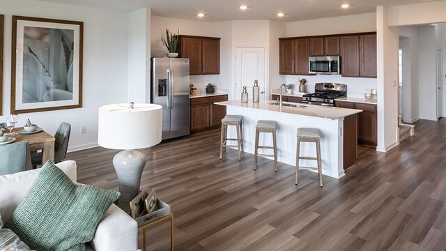 kitchen with stainless steel appliances, a sink, dark wood finished floors, light countertops, and recessed lighting