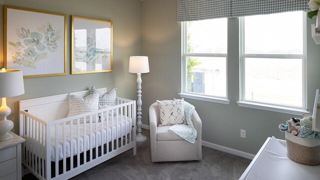 carpeted bedroom featuring multiple windows, a crib, and baseboards