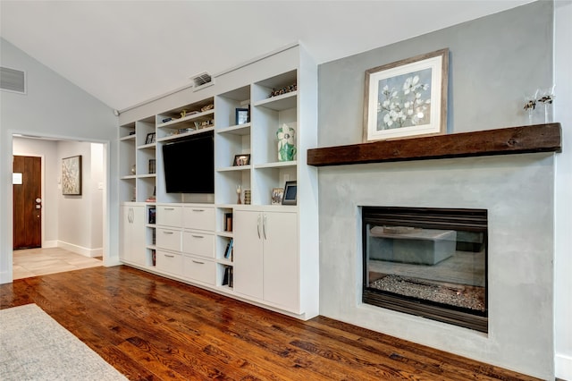 6522 Willow Ln, Dallas, TX 75230 - unfurnished living room featuring wood finished floors, lofted ceiling, and a glass covered fireplace