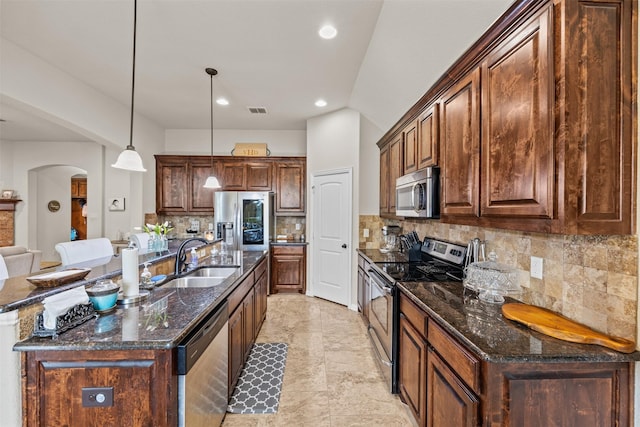 2725 Buffalo Run, Burleson, TX 76028 - kitchen featuring appliances with stainless steel finishes, a sink, arched walkways, tasteful backsplash, and hanging light fixtures