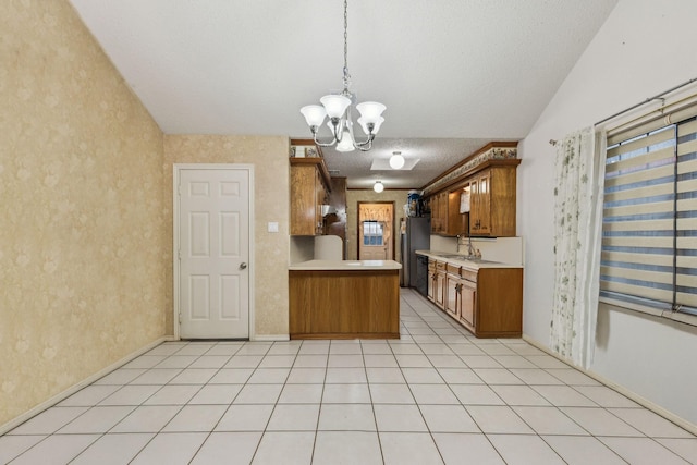 320 Conger Dr, Mesquite, TX 75149 - kitchen with brown cabinetry, light countertops, a chandelier, freestanding refrigerator, and a peninsula