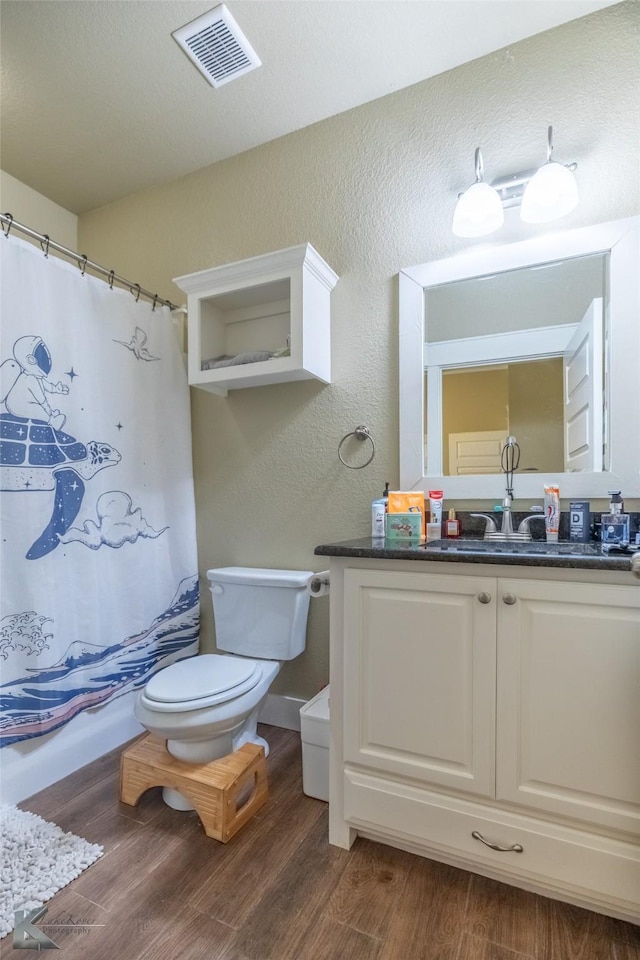 1001 Cabernet Dr, Abilene, TX 79601 - bathroom with vanity, wood finished floors, a textured wall, toilet, and curtained shower