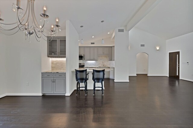 kitchen featuring gray cabinets, decorative backsplash, beam ceiling, a chandelier, and a kitchen breakfast bar
