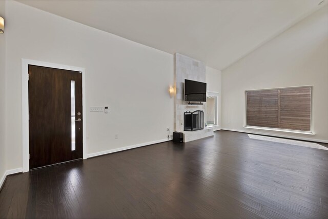 unfurnished living room with dark wood-style floors, a large fireplace, high vaulted ceiling, and baseboards