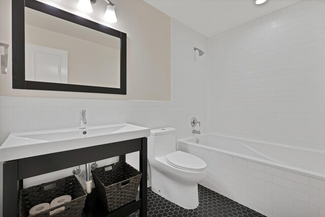 full bathroom featuring tile walls, toilet, tiled shower / bath, tile patterned flooring, and vanity