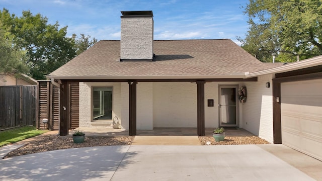 view of front of house with fence, a chimney, a shingled roof, and driveway