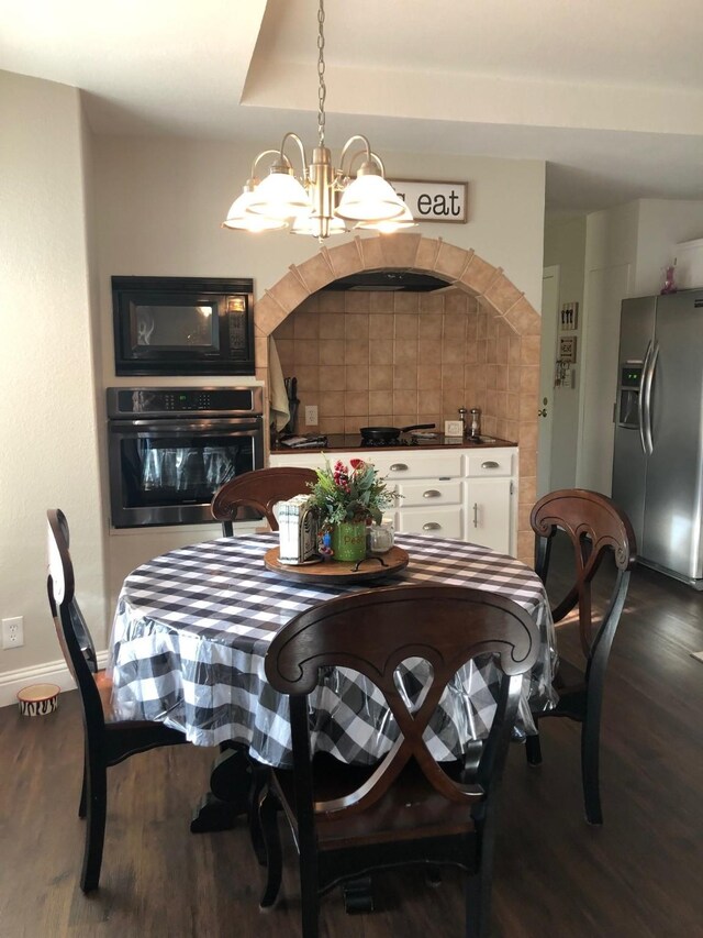 dining area with dark wood-type flooring, a chandelier, and baseboards