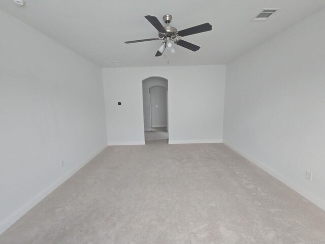 unfurnished room with arched walkways, light colored carpet, ceiling fan, and baseboards
